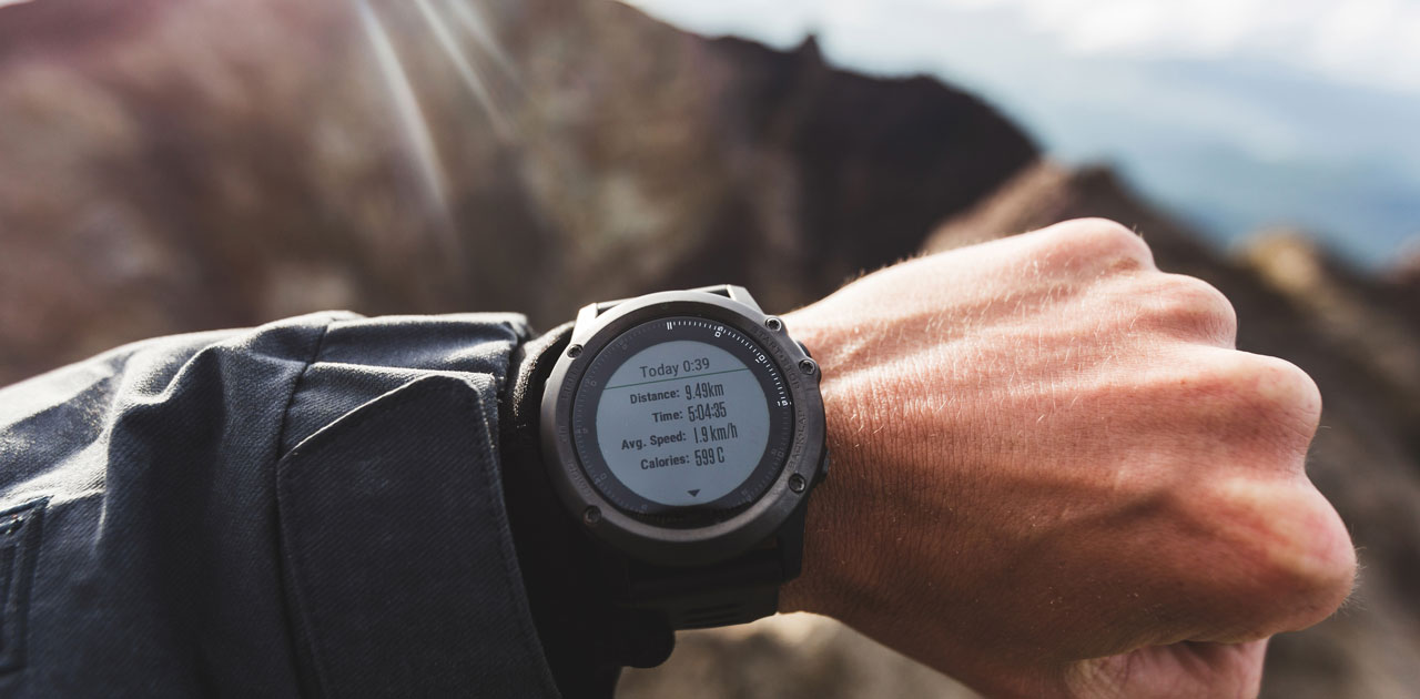 Fitness tracker displaying distance, time, average speed, and calories burned, worn on a wrist in an outdoor setting, emphasizing fitness monitoring and goal achievement.