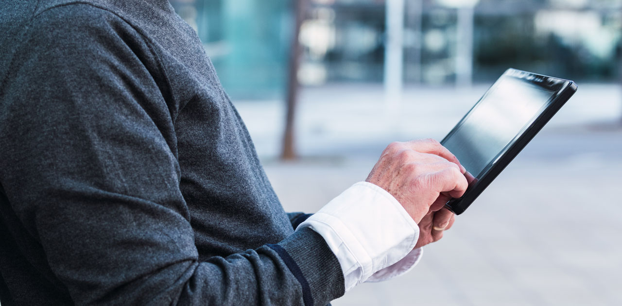 Person using a digital tablet outdoors, illustrating the concept of digital planning and productivity tools for professionals.