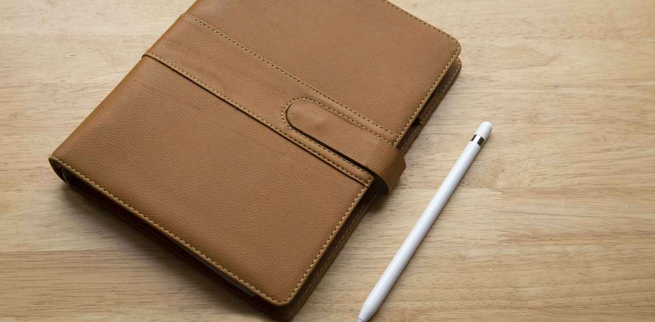 Brown leather planner with a pen, representing the transition from physical planner pads to digital planning tools for improved organization and productivity.