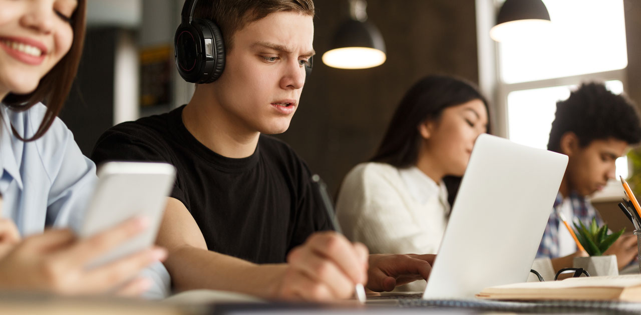 Students engaged in studying with laptops and digital devices, focusing on organization and productivity for the school year.