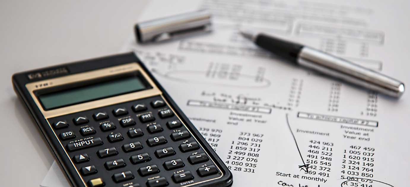 Calculator and pen on financial documents, emphasizing business planning and management.