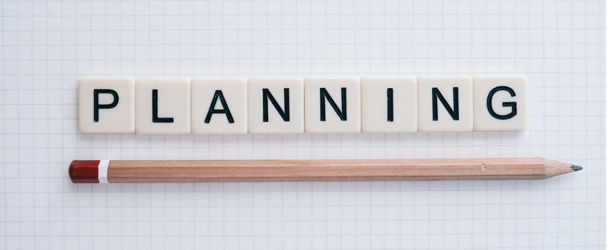 Planning spelled out in letter tiles with a pencil on graph paper, symbolizing organization and strategy for business identity development.