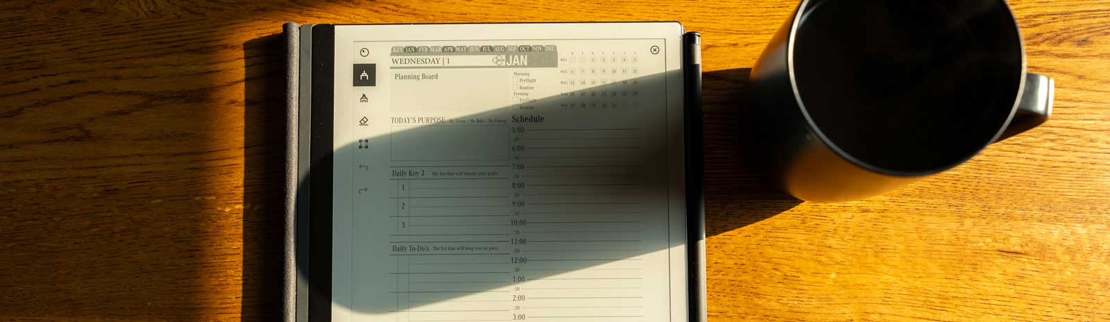 reMarkable 2 digital planner on a wooden table with a coffee mug, featuring a schedule layout and daily planning sections, illustrating effective goal management for Key2Success subscription users.