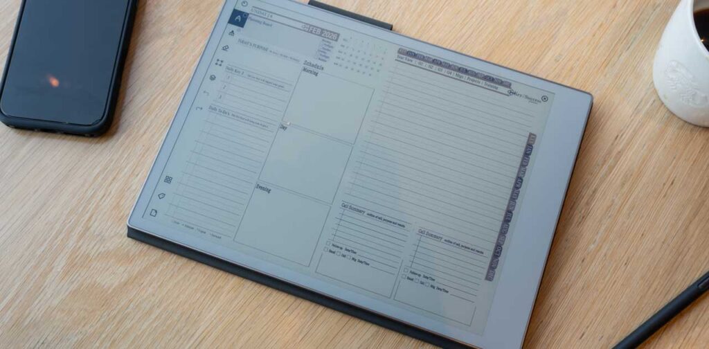 Digital planner on a tablet displaying daily and weekly layouts, alongside a smartphone and coffee cup, representing productivity and organization for professionals and freelancers.