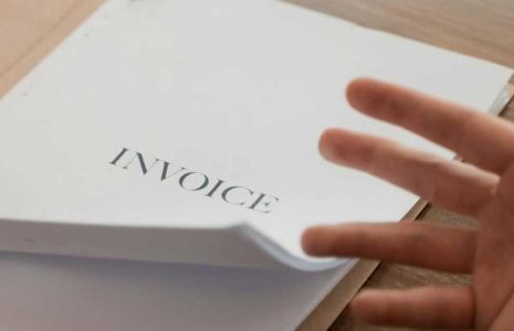 invoice papers being looked at by a human hand paging through